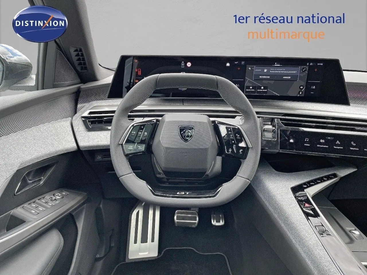 Vue intérieure centrée sur le volant GT du Peugeot 5008 Hybrid 2025 avec tableau de bord numérique et finitions grises.