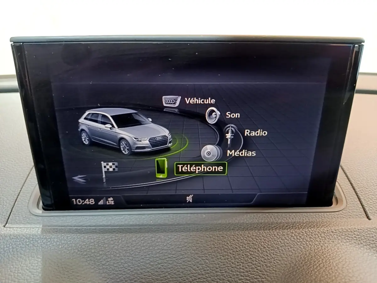 Écran central affichant la voiture Audi A3 gris foncé en vue 3/4 avant avec menu multimédia et téléphone sélectionné.