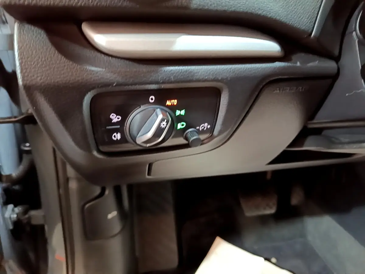 Gros plan sur le panneau de commande des phares à gauche du volant dans l'Audi A3 gris foncé 30 TDI 2019.