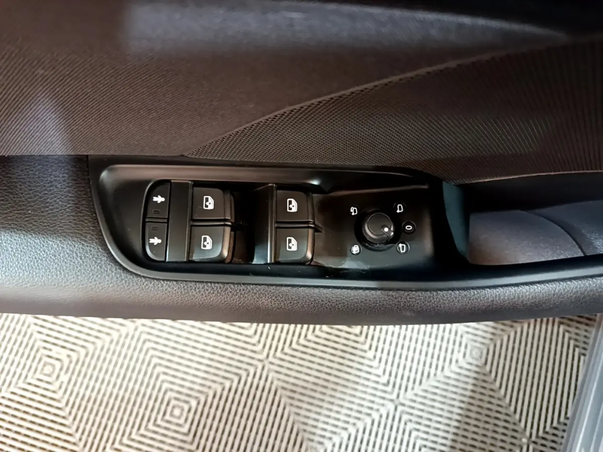 Gros plan sur les commandes de lève-vitres et réglage des rétroviseurs côté conducteur d'une Audi A3 gris foncé.