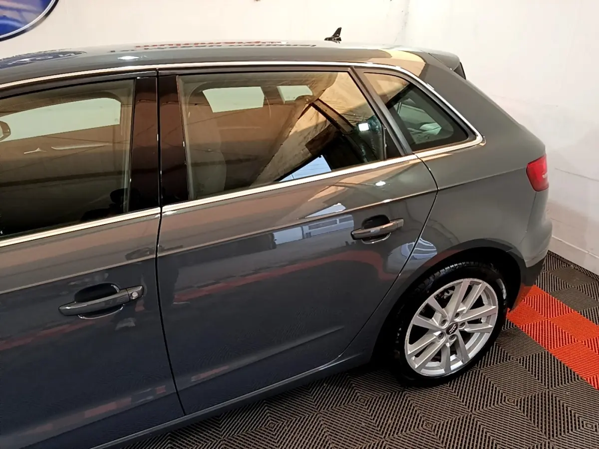 Vue latérale droite d'une Audi A3 gris foncé, mettant en valeur les jantes alliage et les lignes épurées du profil arrière.