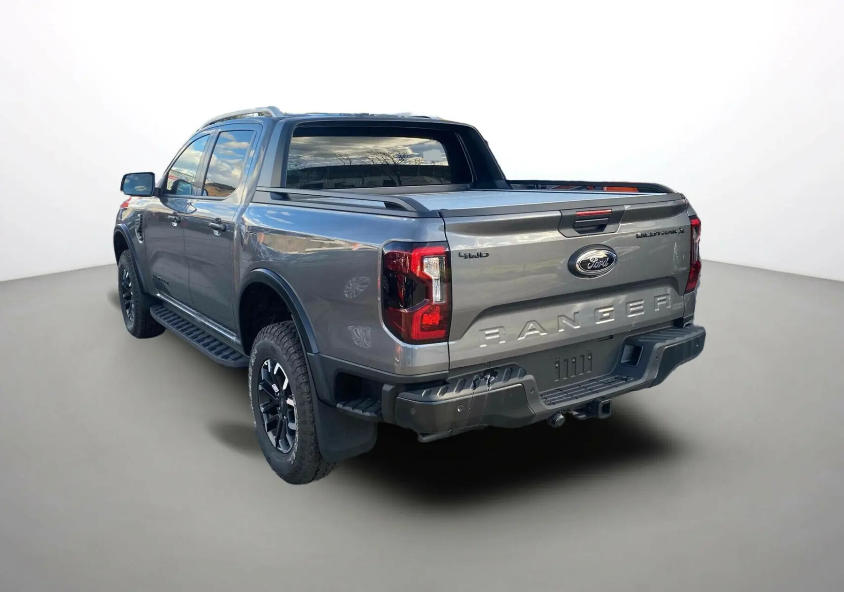 Ford Ranger gris carbone vu en 3/4 arrière droit avec benne couverte et jantes noires.