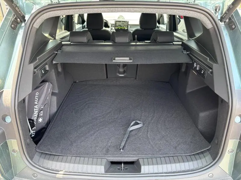 Coffre ouvert du Dacia Bigster blanc, vue arrière montrant l'espace de chargement avec cache-bagages et kit de sécurité.