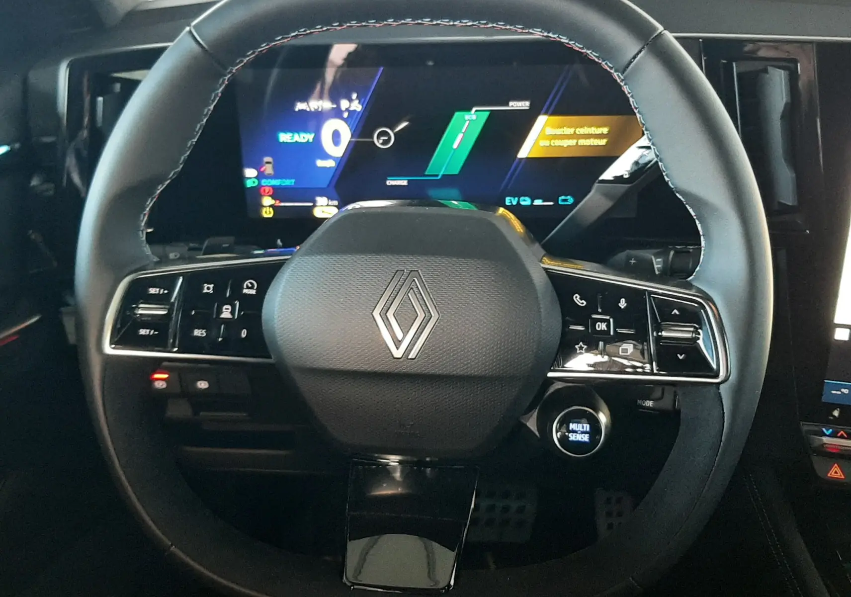 Vue rapprochée du volant noir avec logo Renault, tableau de bord numérique allumé en arrière-plan dans un Renault Austral 2025.