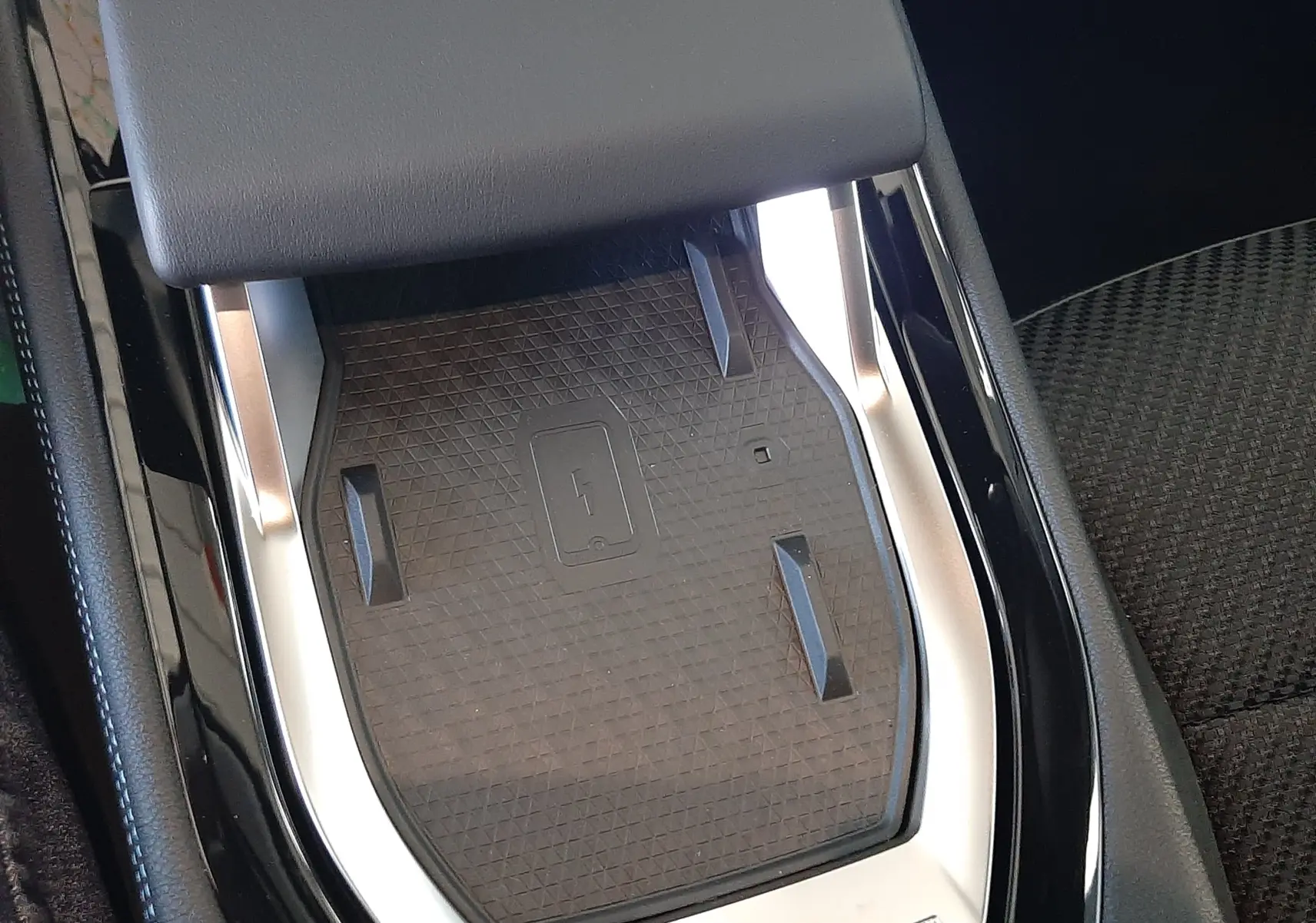 Gros plan sur le chargeur sans fil intégré à la console centrale noire du Renault Austral 2025.