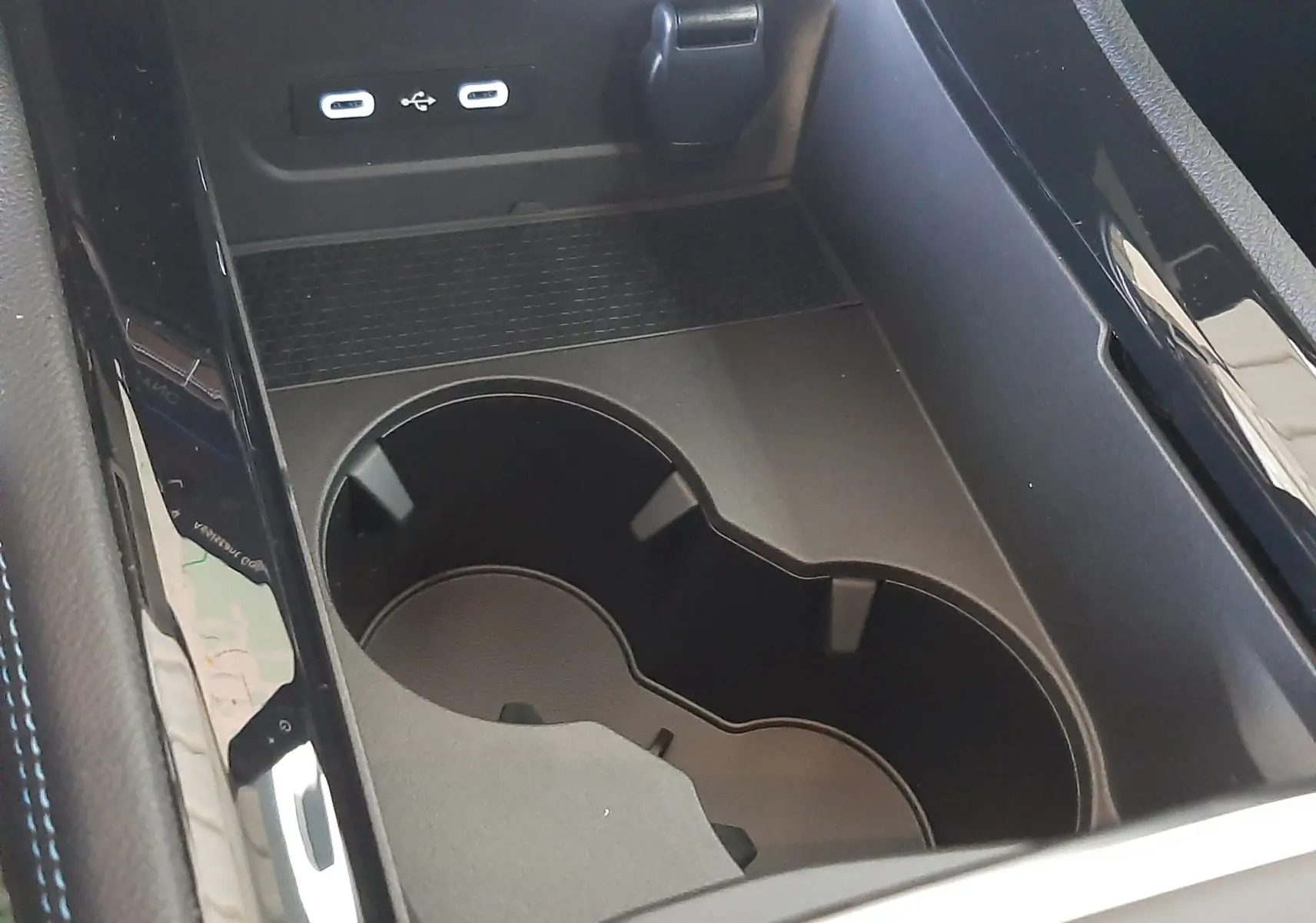 Gros plan sur la console centrale noire du Renault Austral E-Tech avec porte-gobelets et ports USB visibles.