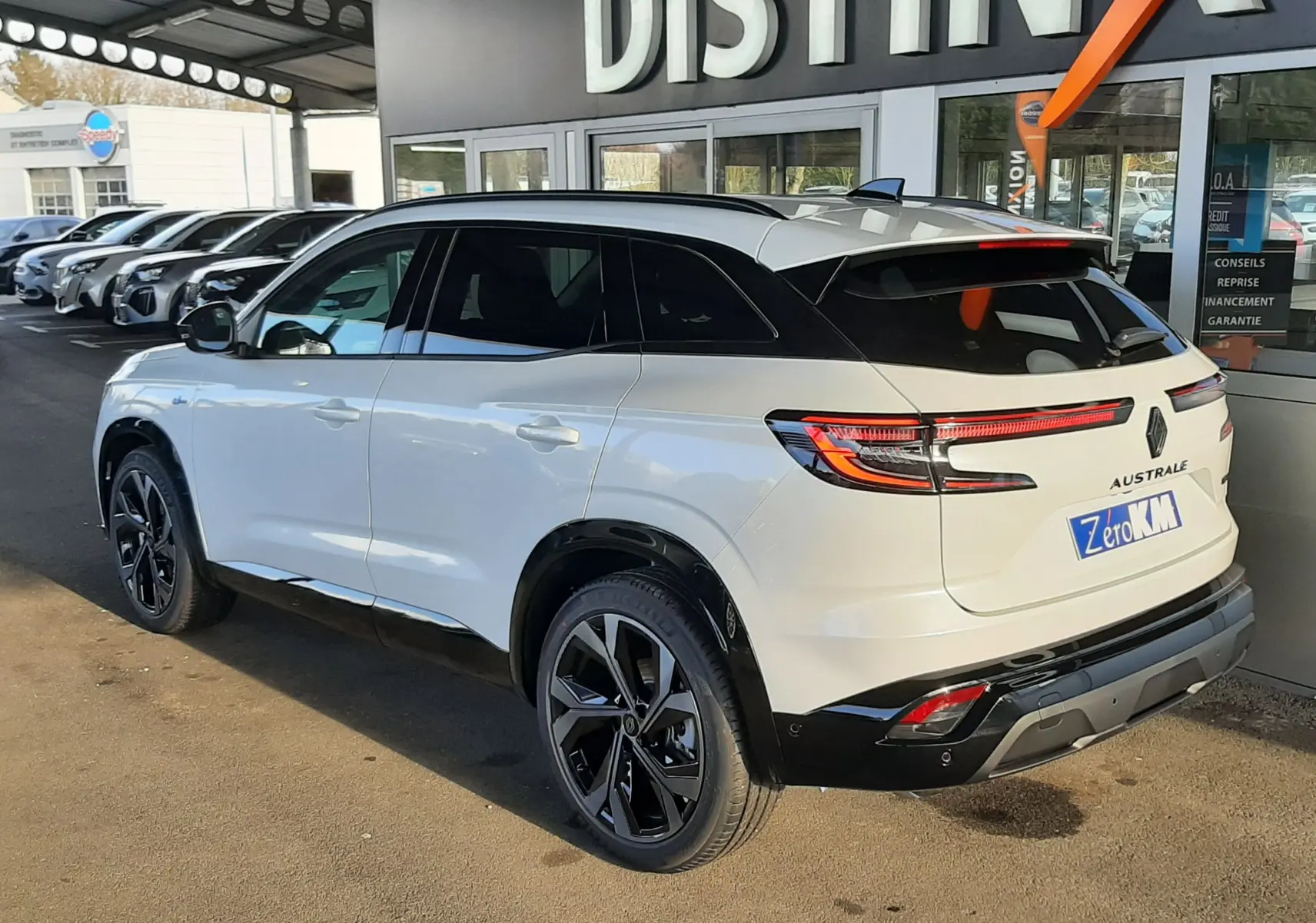 Vue 3/4 arrière droite du Renault Austral blanc nacré avec toit noir, feux arrière LED et jantes noires distinctives.