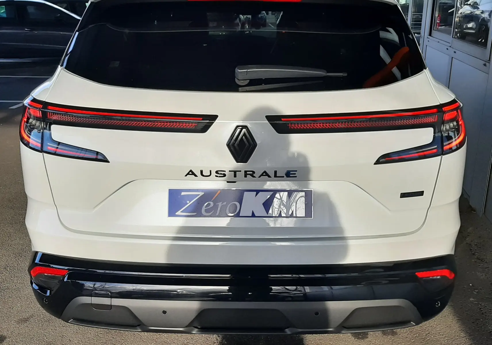 Vue arrière d'un Renault Austral blanc nacré avec toit noir, feux arrière LED étirés et hayon motorisé visible.
