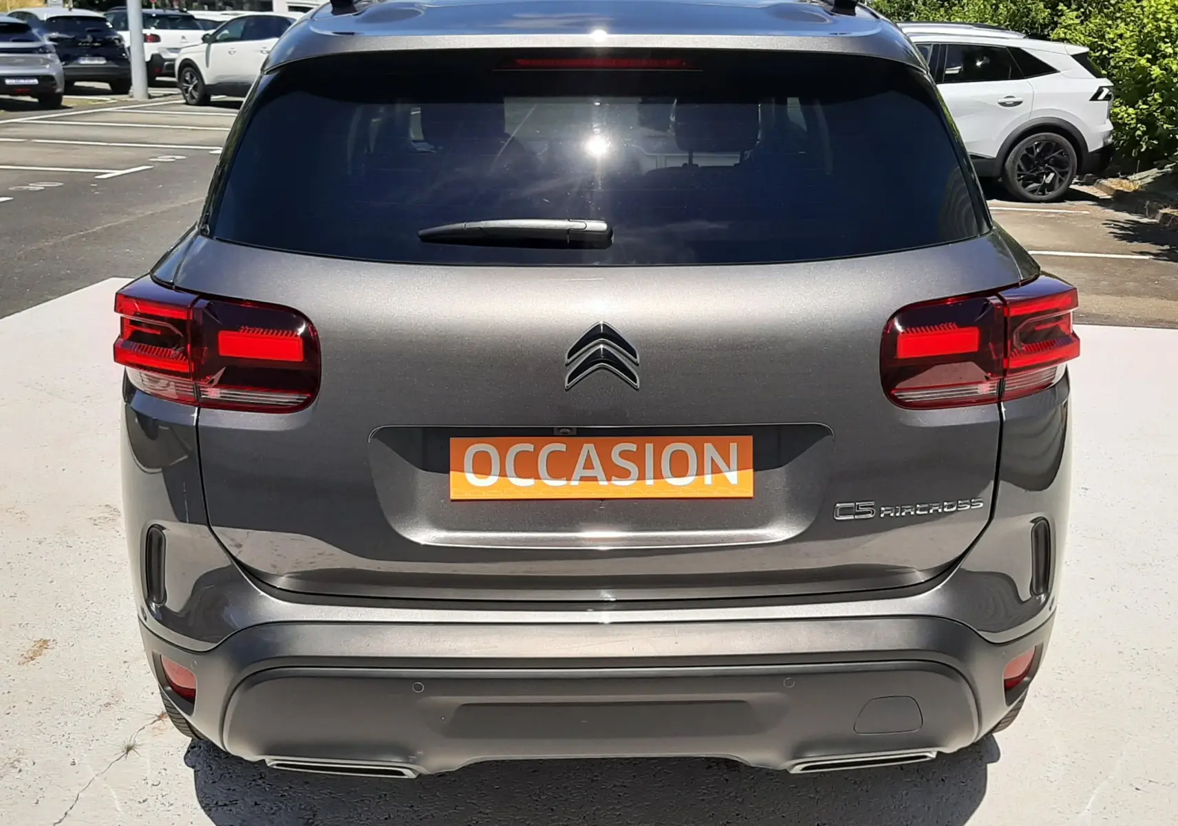 Vue arrière d'un Citroën C5 Aircross hybride gris platinium, avec feux rouges et plaque "OCCASION" visible.
