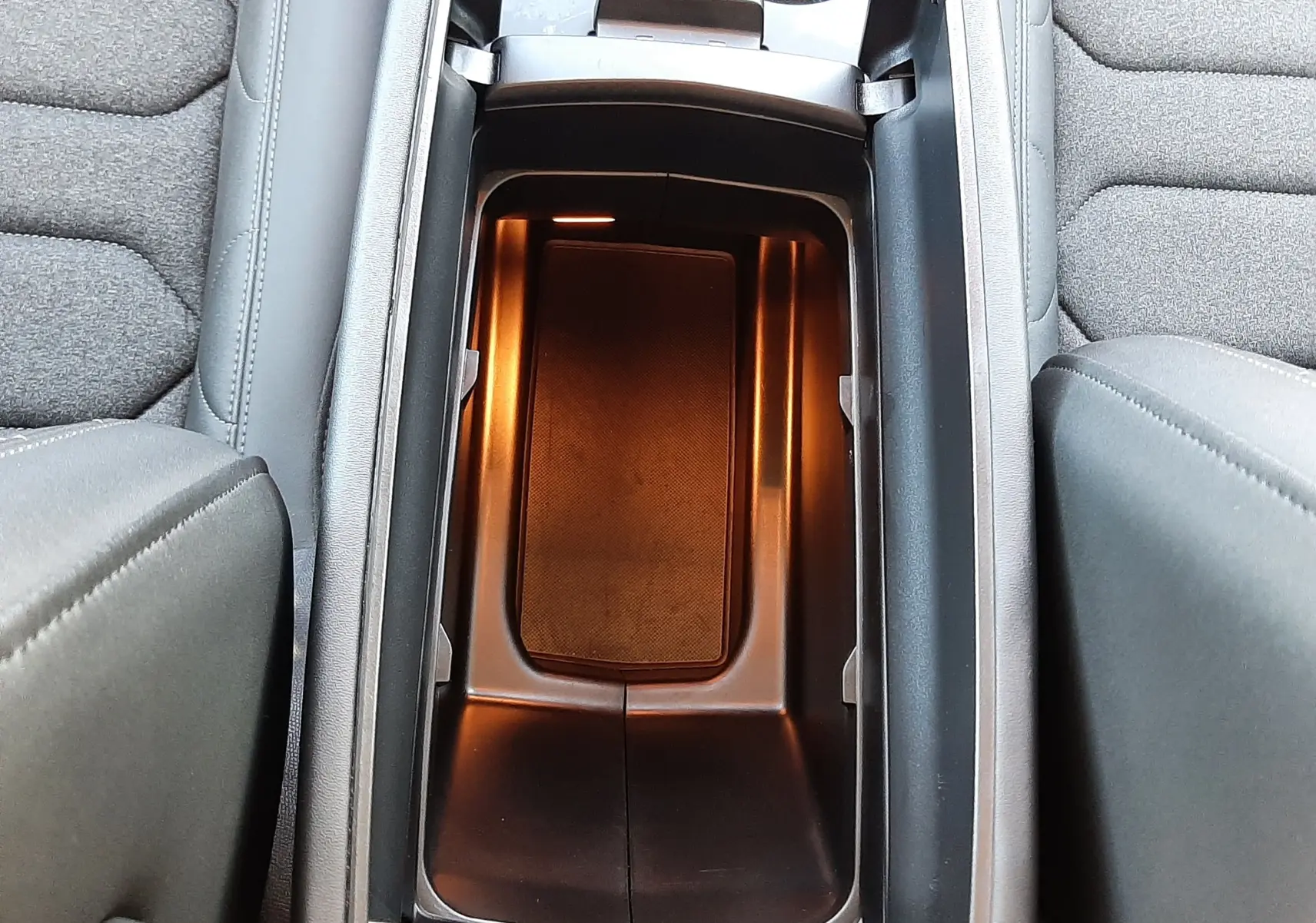 Vue plongeante sur le rangement central éclairé et les sièges gris tissu du Citroën C5 Aircross hybride 2025.
