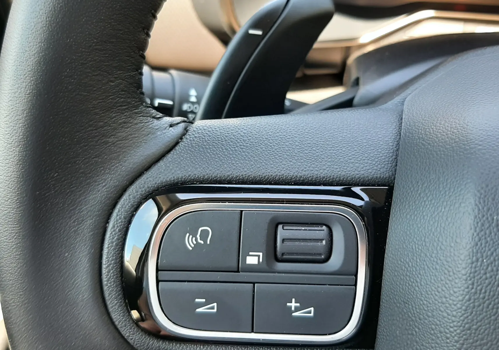 Gros plan sur les commandes multifonctions noires à gauche du volant cuir noir du Citroën C5 Aircross hybride 2025.