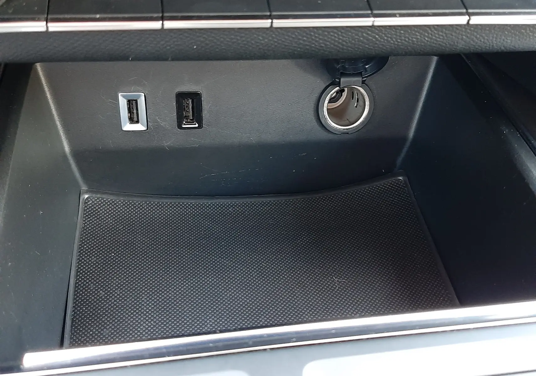 Gros plan sur la console centrale noire du Citroën C5 Aircross hybride 2025 avec ports USB et prise 12V visibles.