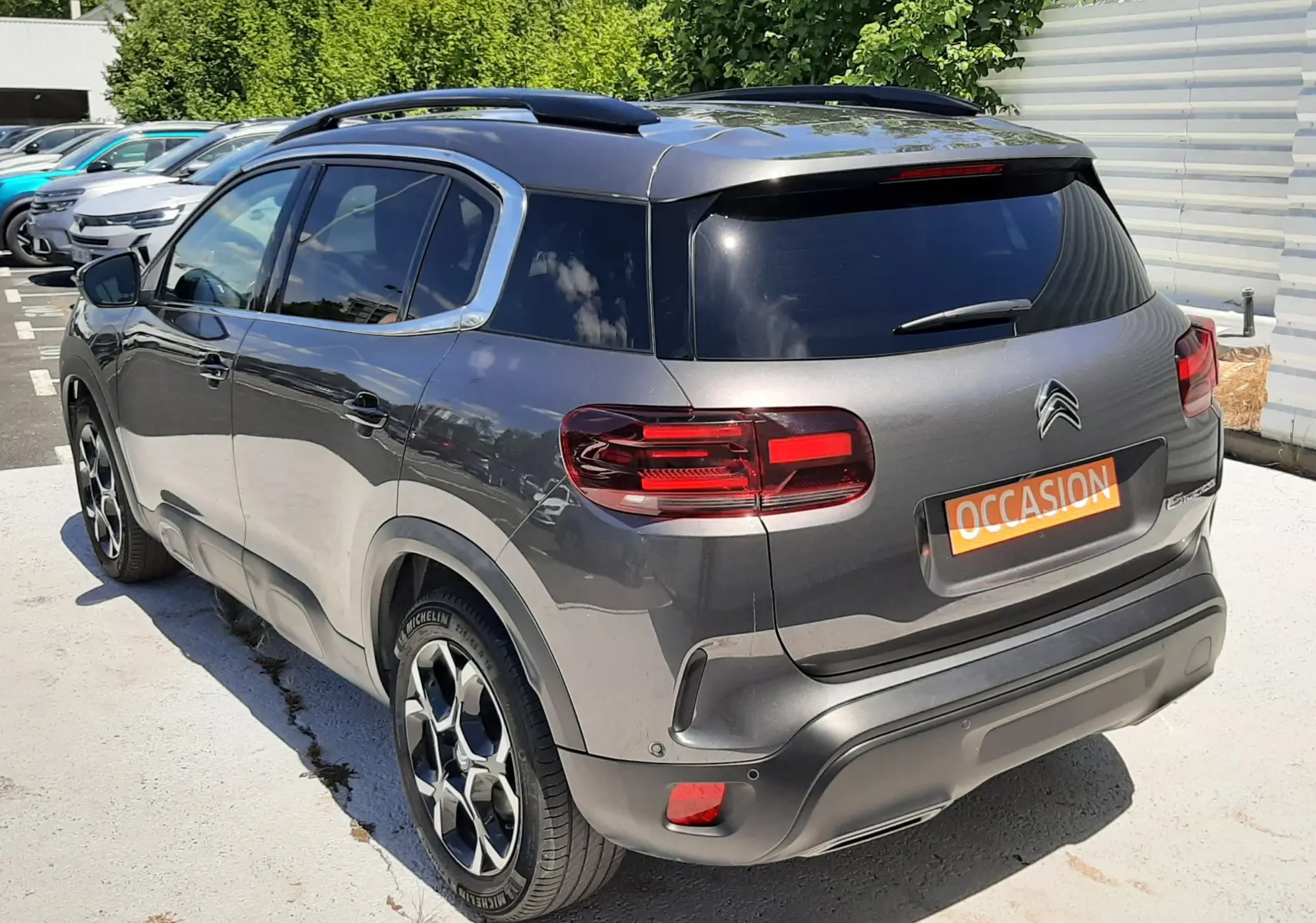 Vue 3/4 arrière droite d’un Citroën C5 Aircross hybride gris platinium avec toit noir et jantes bi-ton.