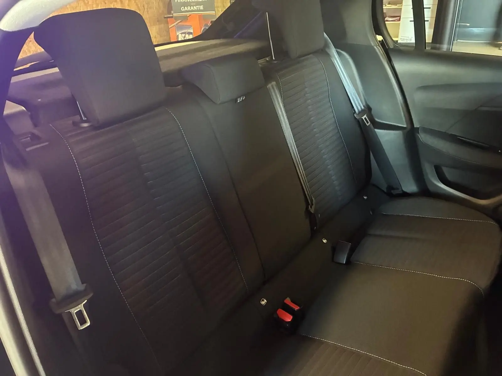 Vue intérieure de la banquette arrière noire en tissu de la Peugeot 208 1.5 BlueHDi 100 Style, avec ceintures visibles.
