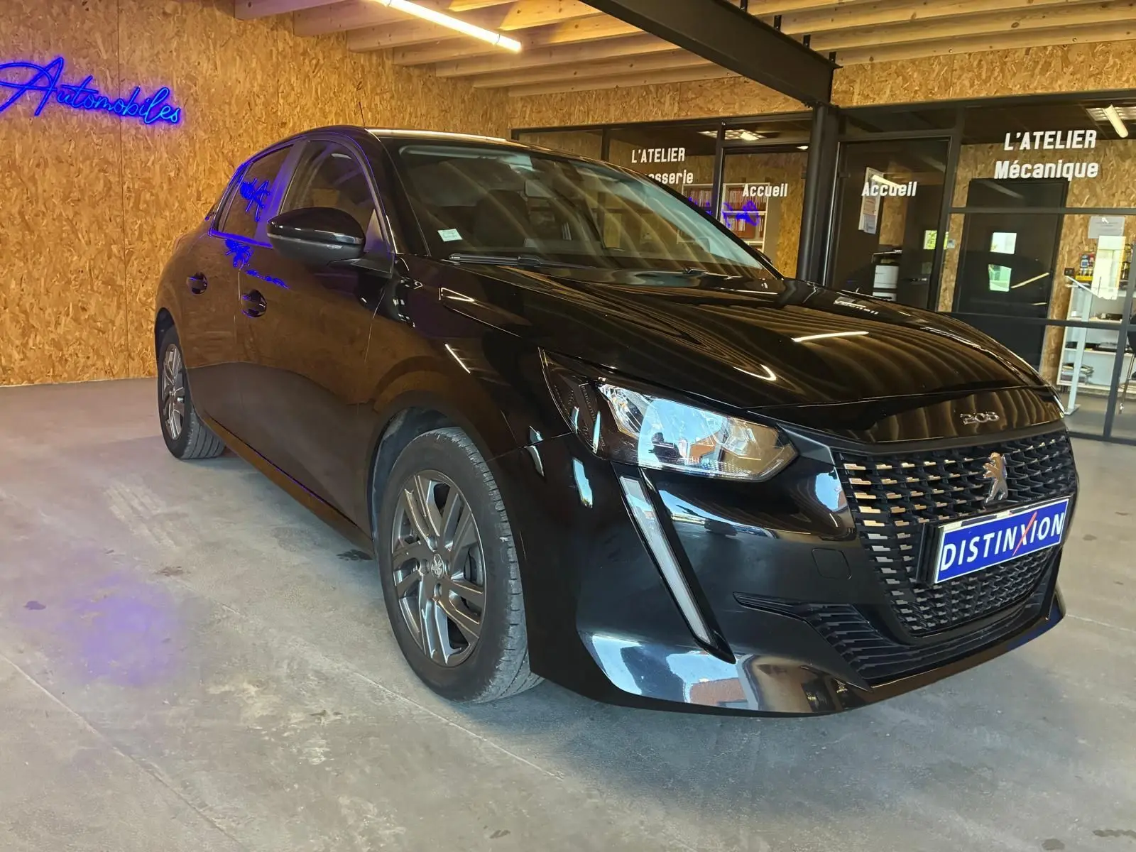 PEUGEOT 208 1.5 BlueHDi 100 Style noir en 3/4 avant droit, avec calandre distinctive et phares LED.