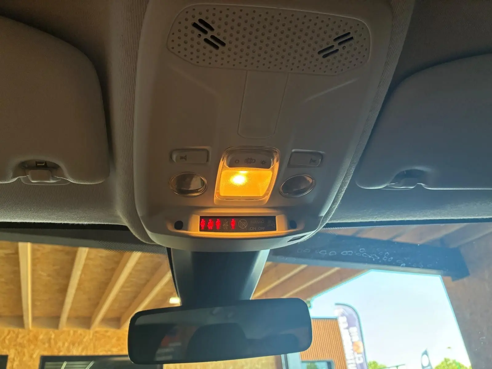 Plafonnier allumé vu de l’intérieur avant d’une Peugeot 208 noire 1.5 BlueHDi 2021 avec rétroviseur central.