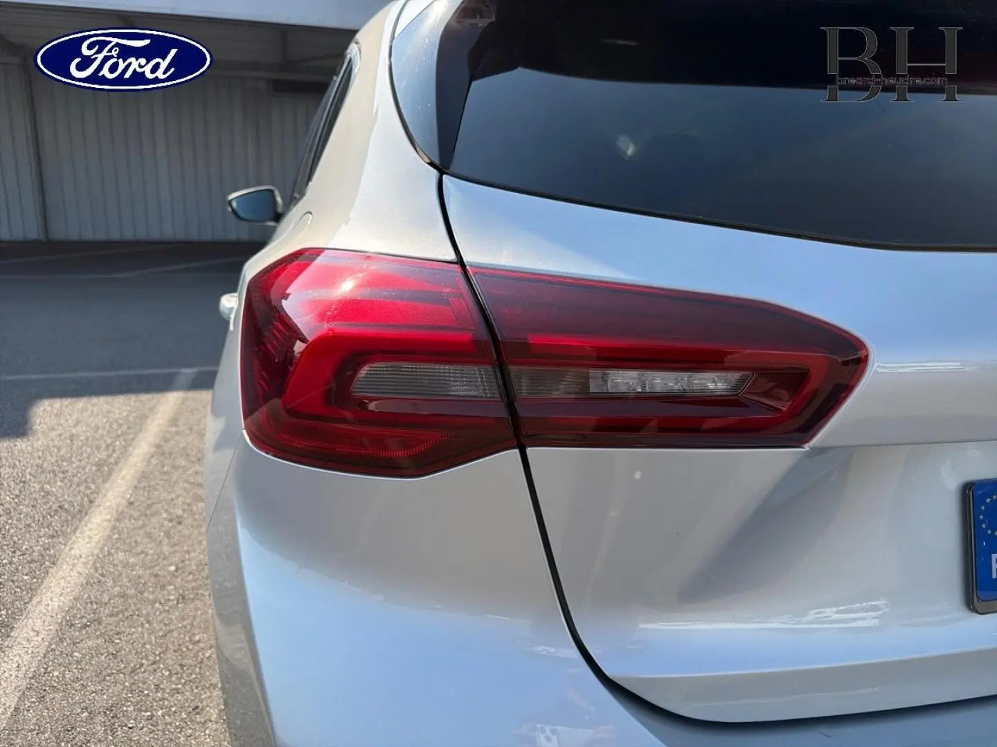 Gros plan sur le feu arrière gauche d'une Ford Focus 2023 gris lunaire métallisé, avec partie de la lunette arrière visible.