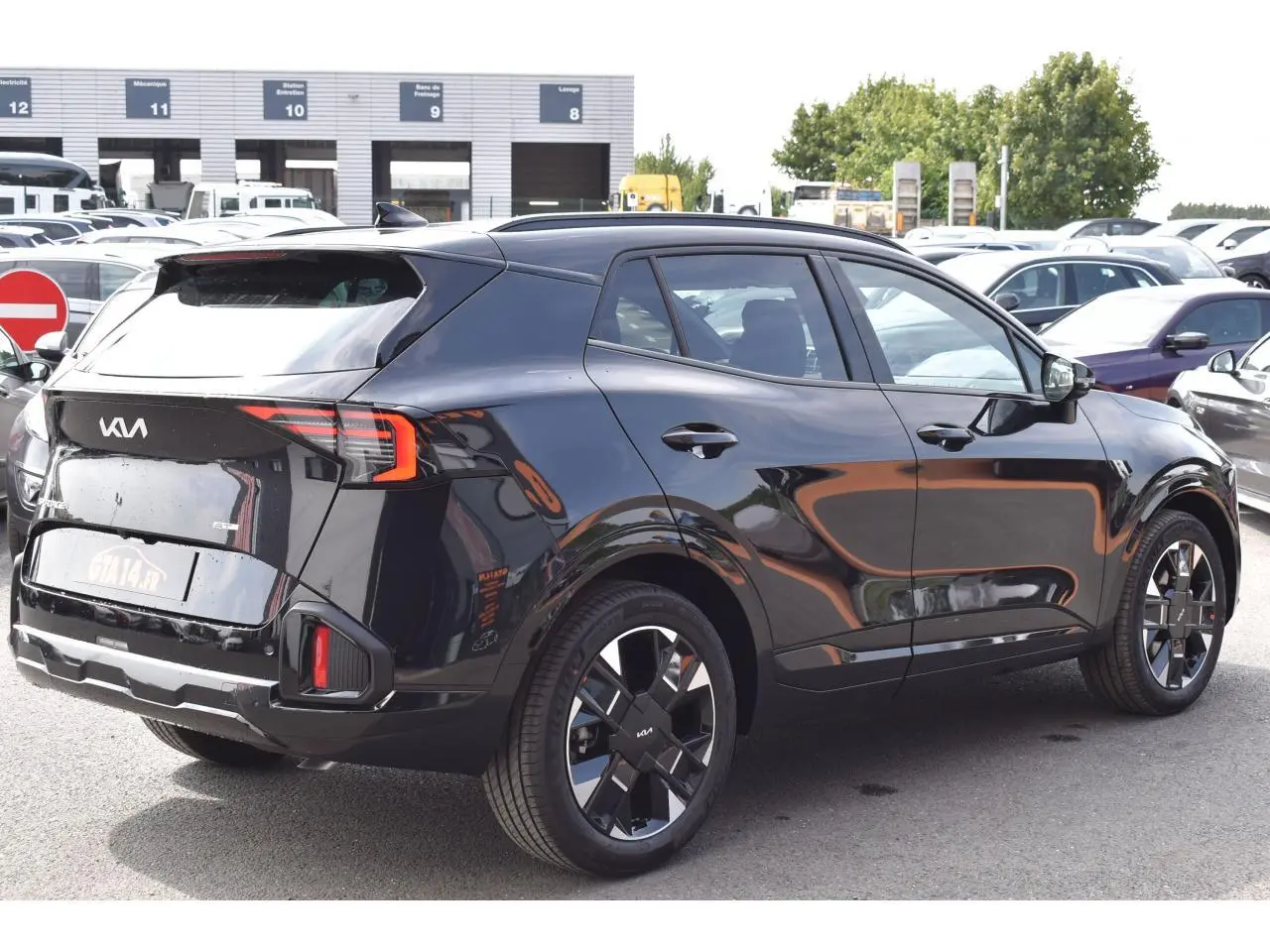 KIA Sportage hybride noir vue 3/4 arrière droit, jantes 19 pouces et feux arrière LED distinctifs.