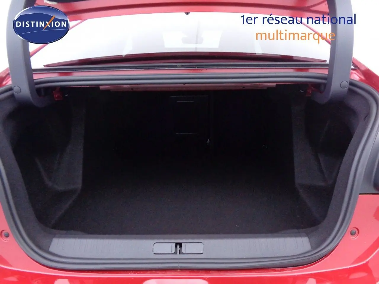 Coffre ouvert vu de l'arrière d'une Citroën C4 X rouge Elixir Métal, montrant l'espace de chargement vide.