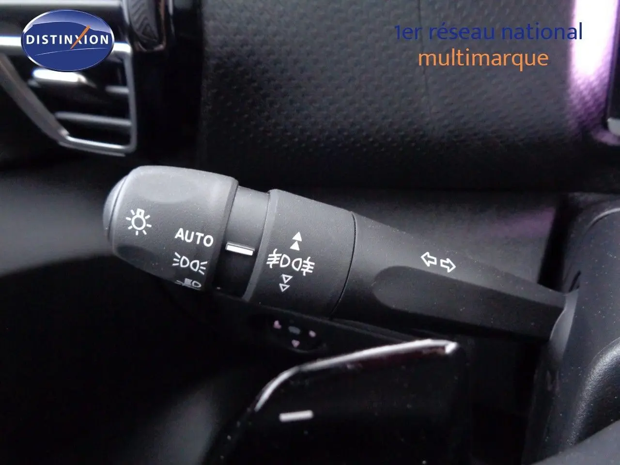 Gros plan sur la commande des phares et clignotants à gauche du volant dans l’habitacle d’une Citroën C4 X rouge Elixir Metal.