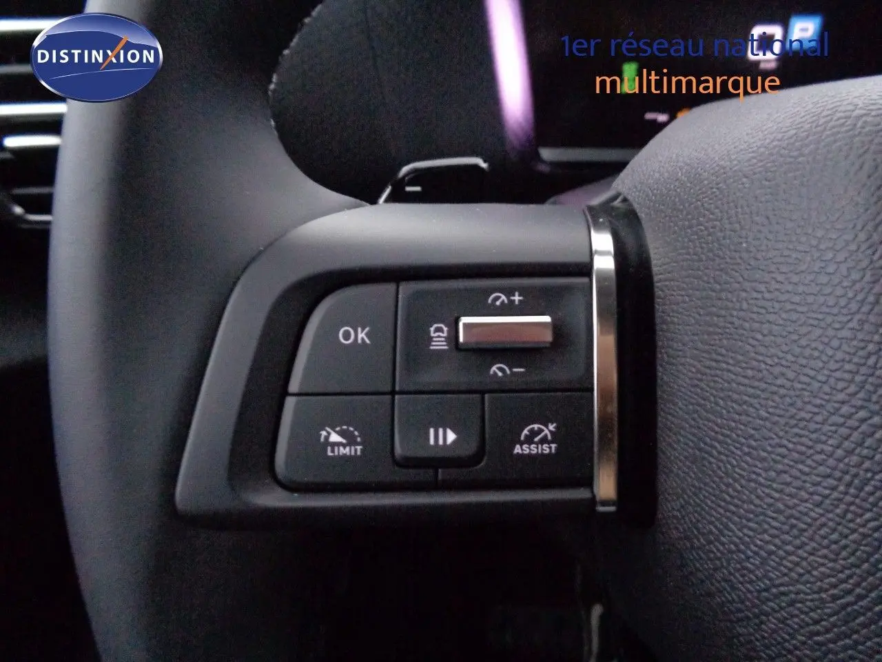 Gros plan sur les commandes au volant à gauche du Citroën C4 X rouge Elixir Metal, boutons de limitation et assistance.