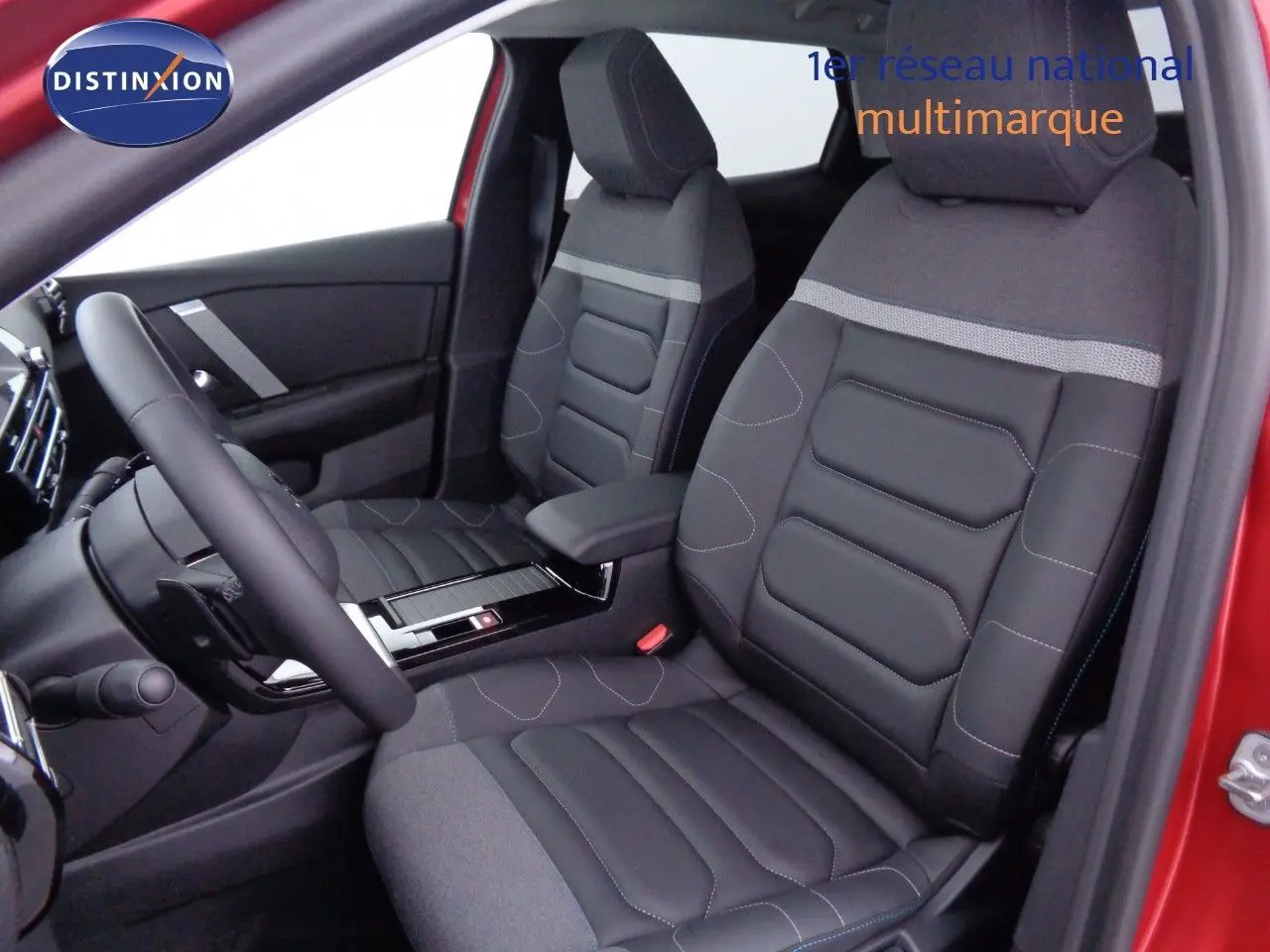 Vue intérieure côté conducteur de la Citroën C4 X rouge Elixir, sièges en tissu et cuir noir avec surpiqûres contrastées.