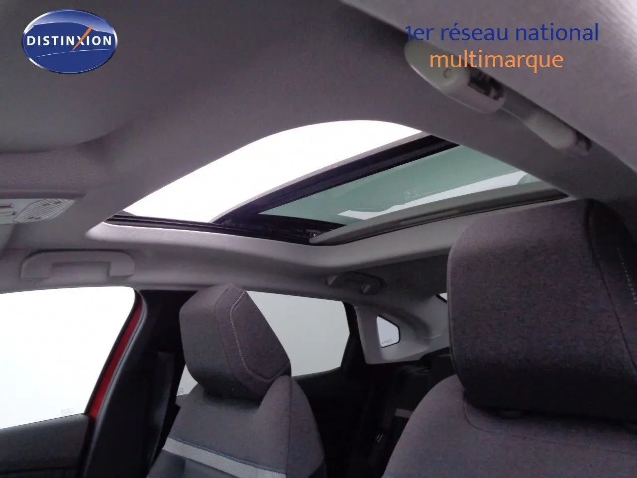 Vue intérieure sur les sièges avant gris et le toit ouvrant panoramique d'une Citroën C4 X rouge Elixir Metal.