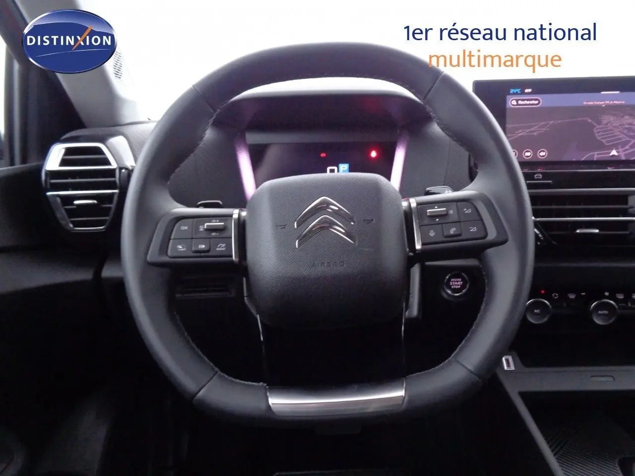 Vue rapprochée du volant noir du Citroën C4 X 2023 avec commandes intégrées et tableau de bord numérique.