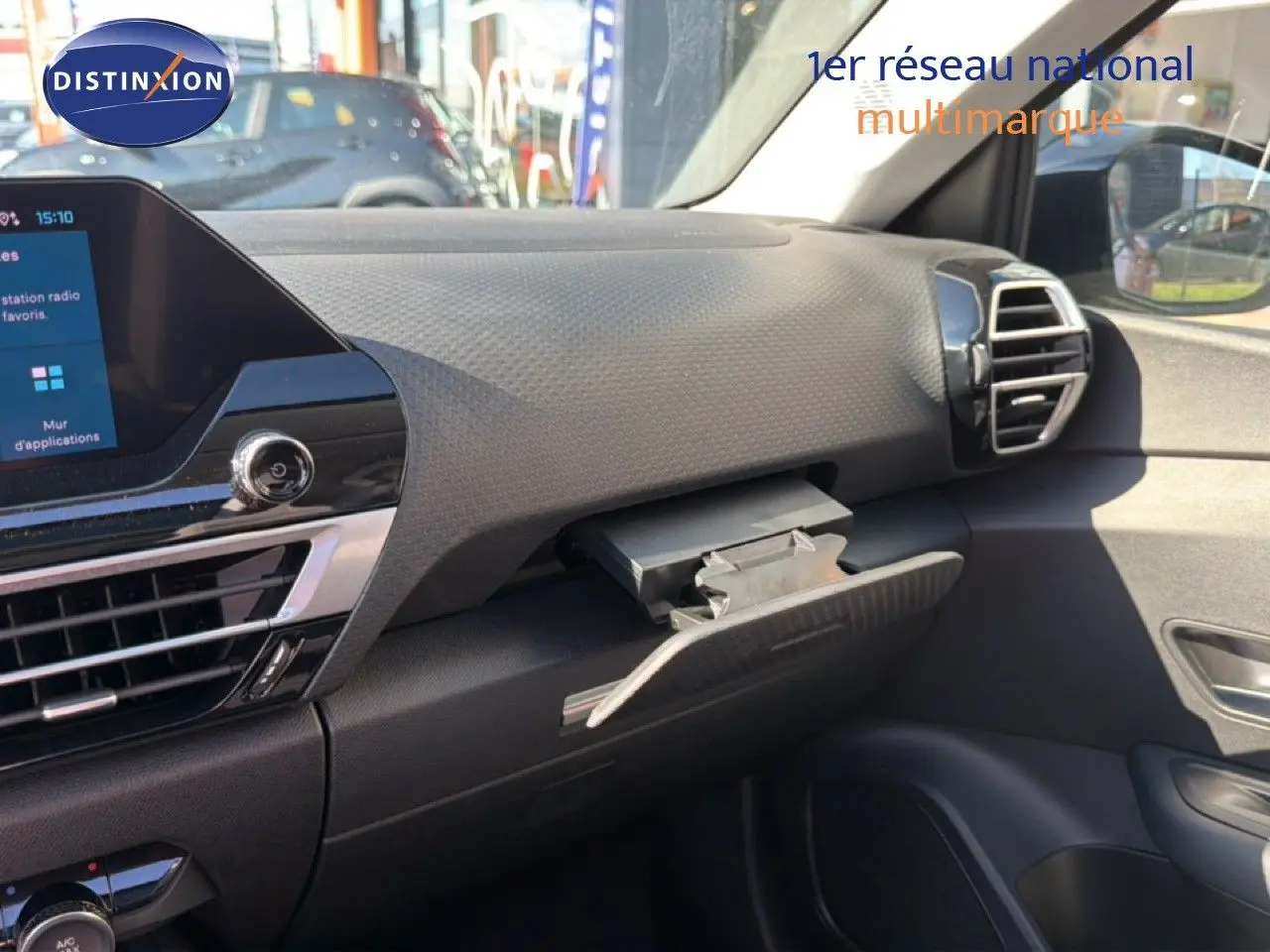 Vue intérieure côté passager du tableau de bord noir du Citroën C4 X 2023 avec boîte à gants ouverte.