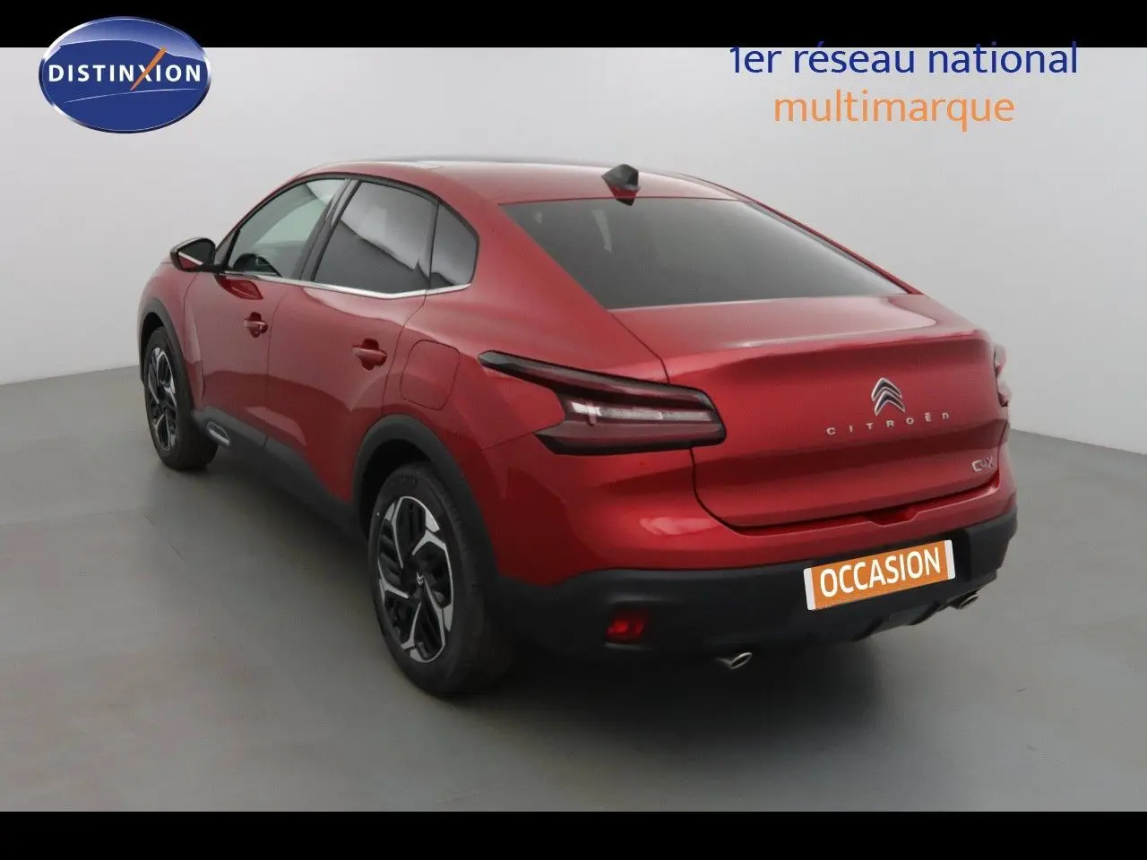 Vue 3/4 arrière droite d'une Citroën C4 X rouge Elixir métal avec feux arrière LED et jantes alliage bicolores.