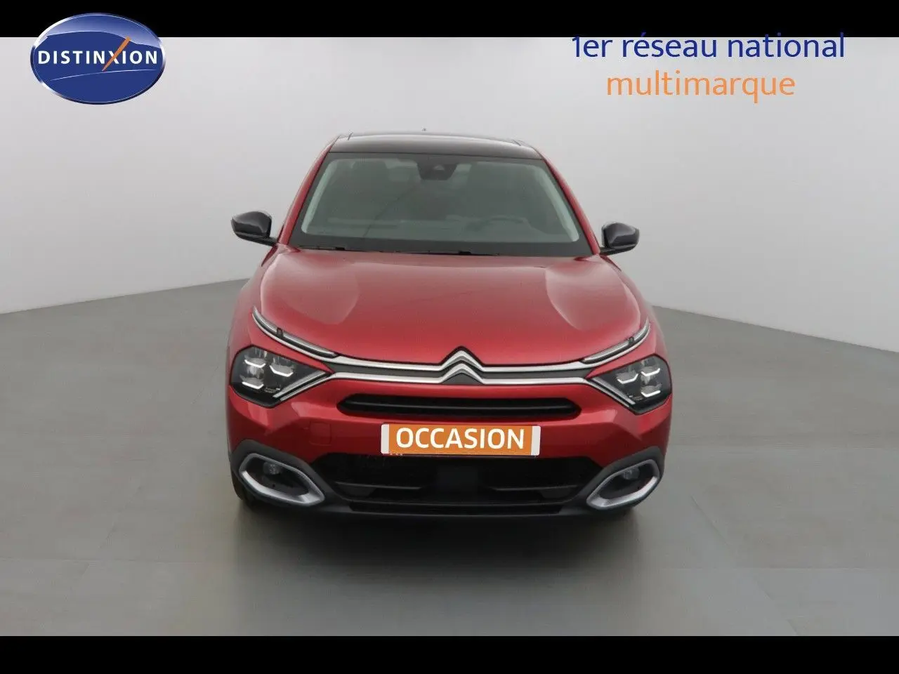 Vue frontale d'une Citroën C4 X rouge Elixir Métal 2023 avec calandre distinctive et feux LED allumés.