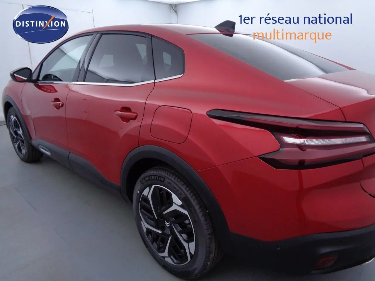 Vue 3/4 arrière droite d'une Citroën C4 X rouge Elixir métal avec feux arrière LED et jantes noires bicolores.