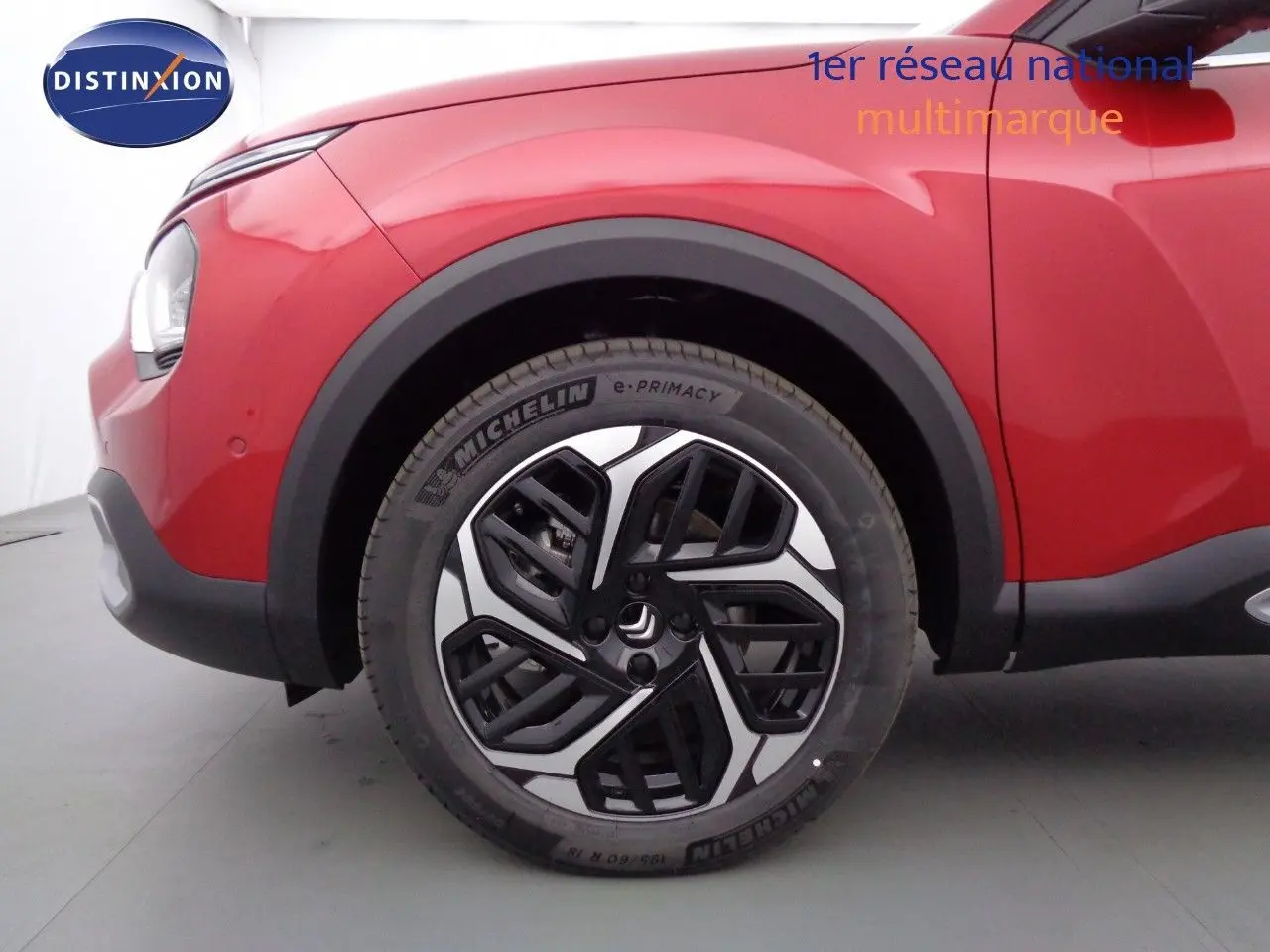 Gros plan sur la roue avant gauche d'une Citroën C4 X rouge Elixir Métal avec jante alliage noire et argent.