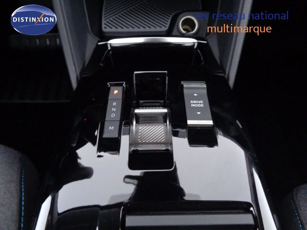 Gros plan sur la console centrale noire brillante de la Citroën C4 X 2023 avec sélecteur de boîte auto et bouton Drive Mode.