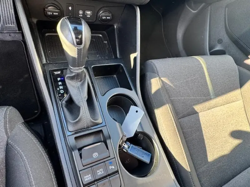 Vue rapprochée de la console centrale noire avec levier de vitesse cuir et clé Hyundai dans porte-gobelets du Tucson Phantom Black 2019.