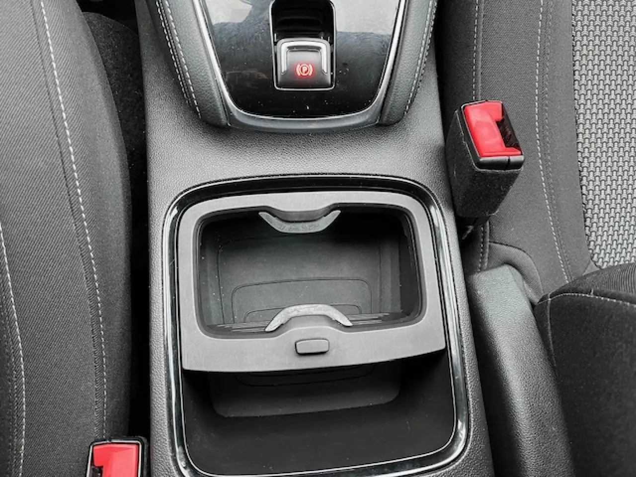 Gros plan sur la console centrale noire de l’Opel Grandland X 2019 avec frein à main électrique et bouton rouge de sécurité.