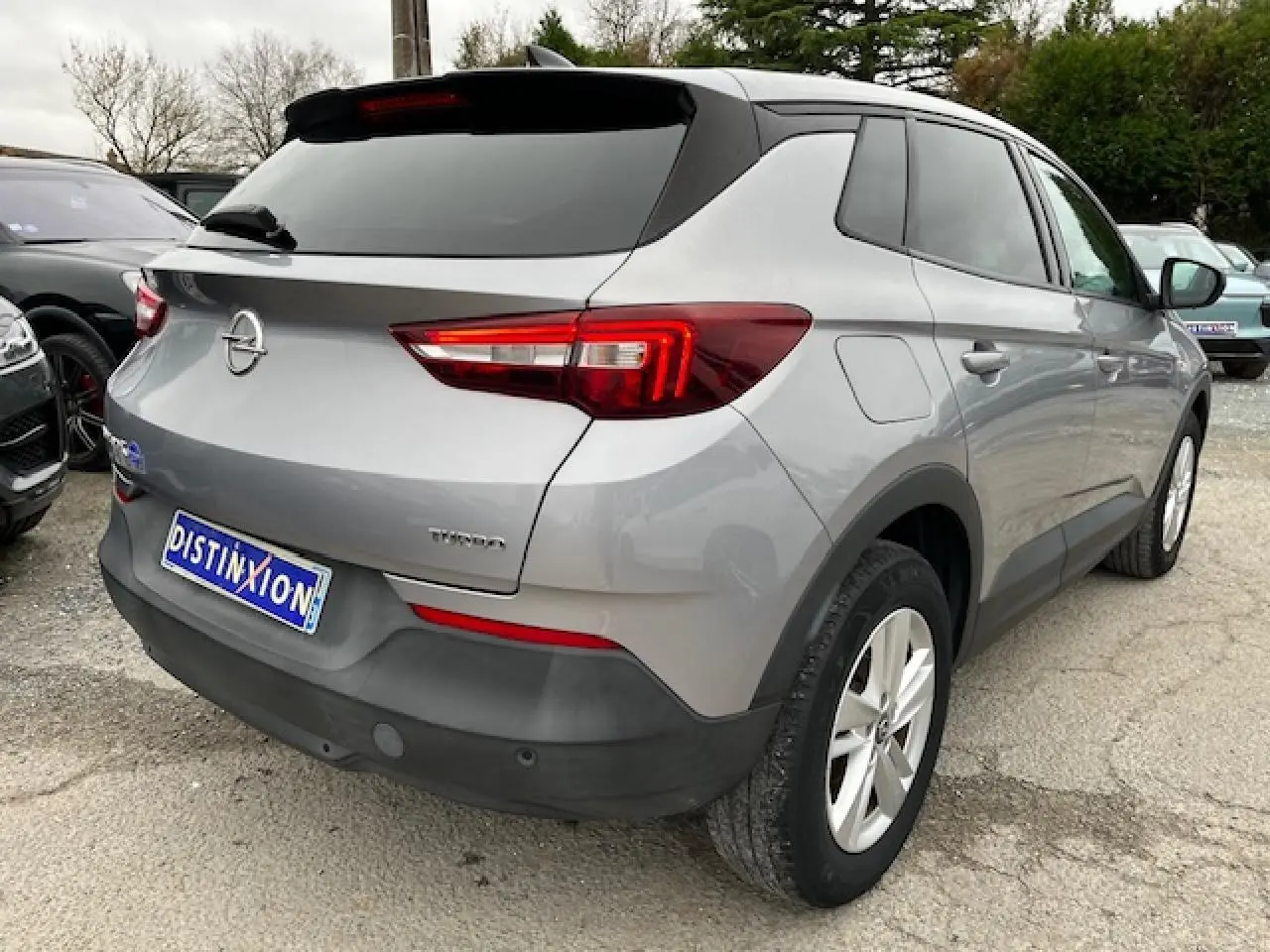 Vue 3/4 arrière droite d'un Opel Grandland X gris clair avec feux arrière LED et jantes alliage 17 pouces.