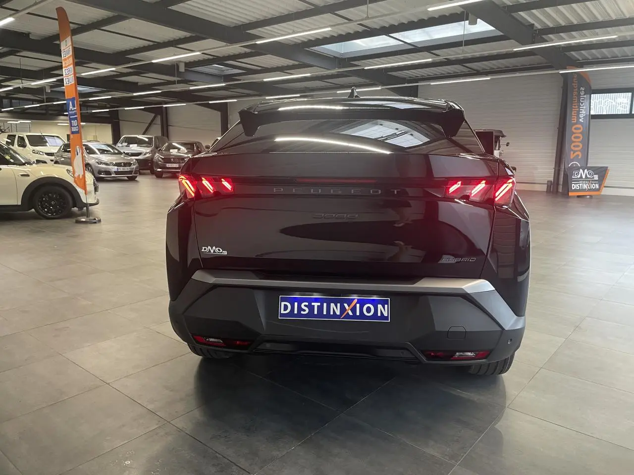 Vue arrière d’un Peugeot 3008 GT hybride noir métallisé avec feux arrière à griffes LED et bandeau noir laqué.