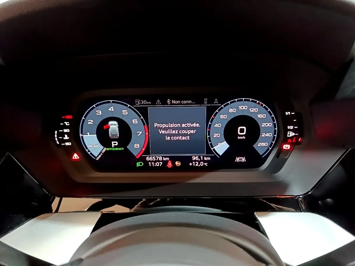 Vue rapprochée du tableau de bord numérique de l'Audi A3 gris foncé, affichant le compteur et les alertes de conduite.