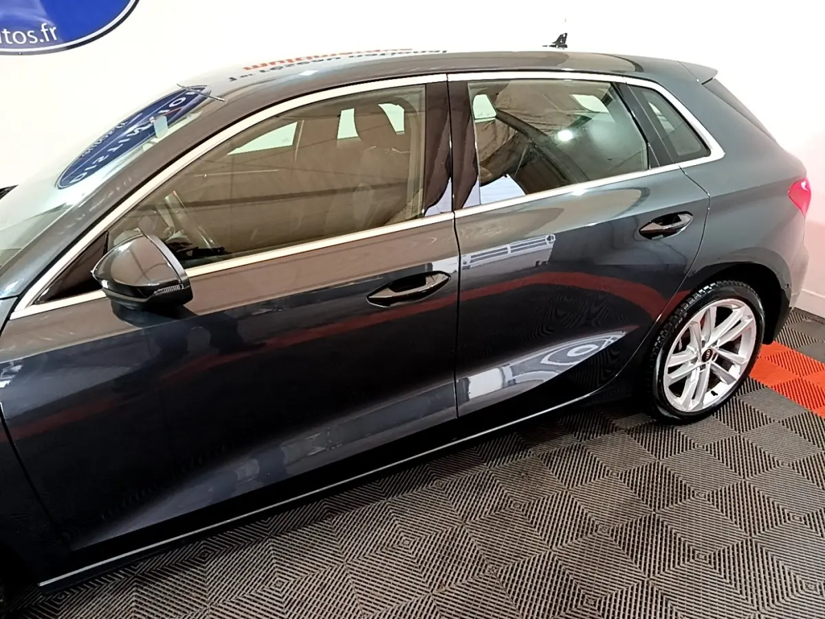 Vue de profil côté gauche d'une Audi A3 gris foncé 35 TFSI 150 MHEV avec jantes alliage et rétroviseurs noirs.