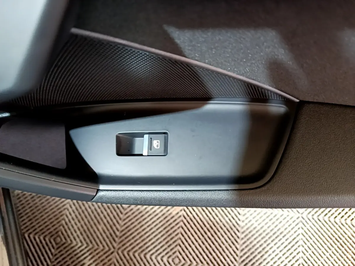 Gros plan sur le bouton de verrouillage des portes dans la portière intérieure noire d'une Audi A3 gris foncé.