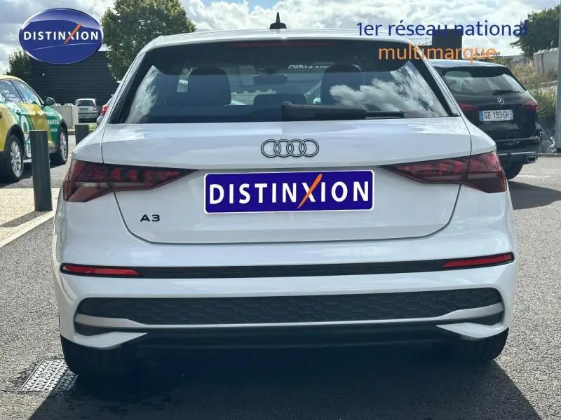 Vue arrière d'une Audi A3 Sportback blanche 2024 avec feux arrière LED et logo Audi bien visible.