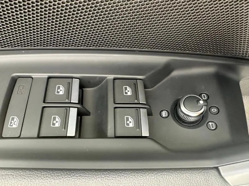 Gros plan sur les commandes de lève-vitres et réglage des rétroviseurs côté conducteur de l'Audi A3 Sportback 2024 en finition Design.