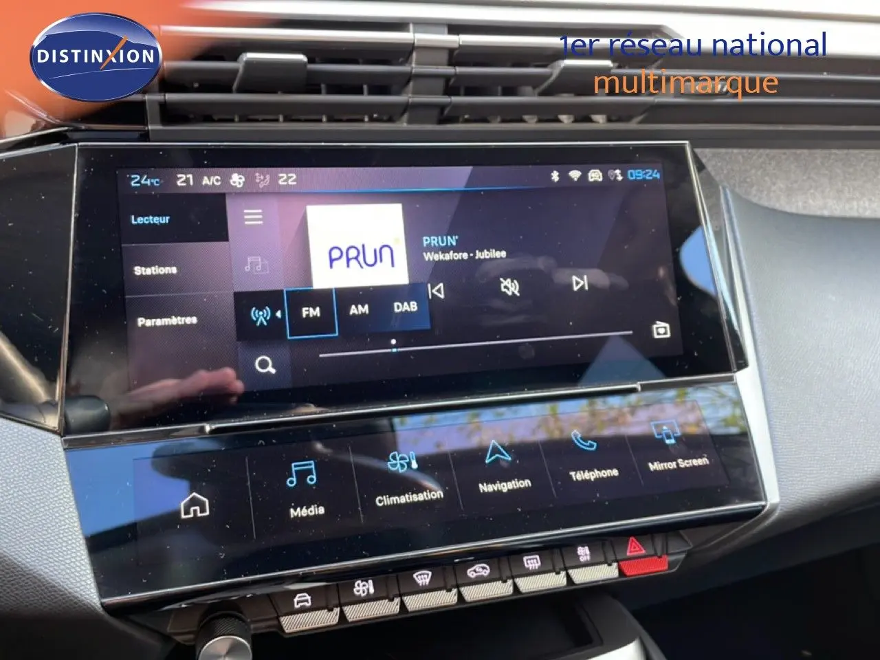 Écran tactile central de la Peugeot 308 2024 montrant l’interface multimédia avec radio FM et commandes climatisation.