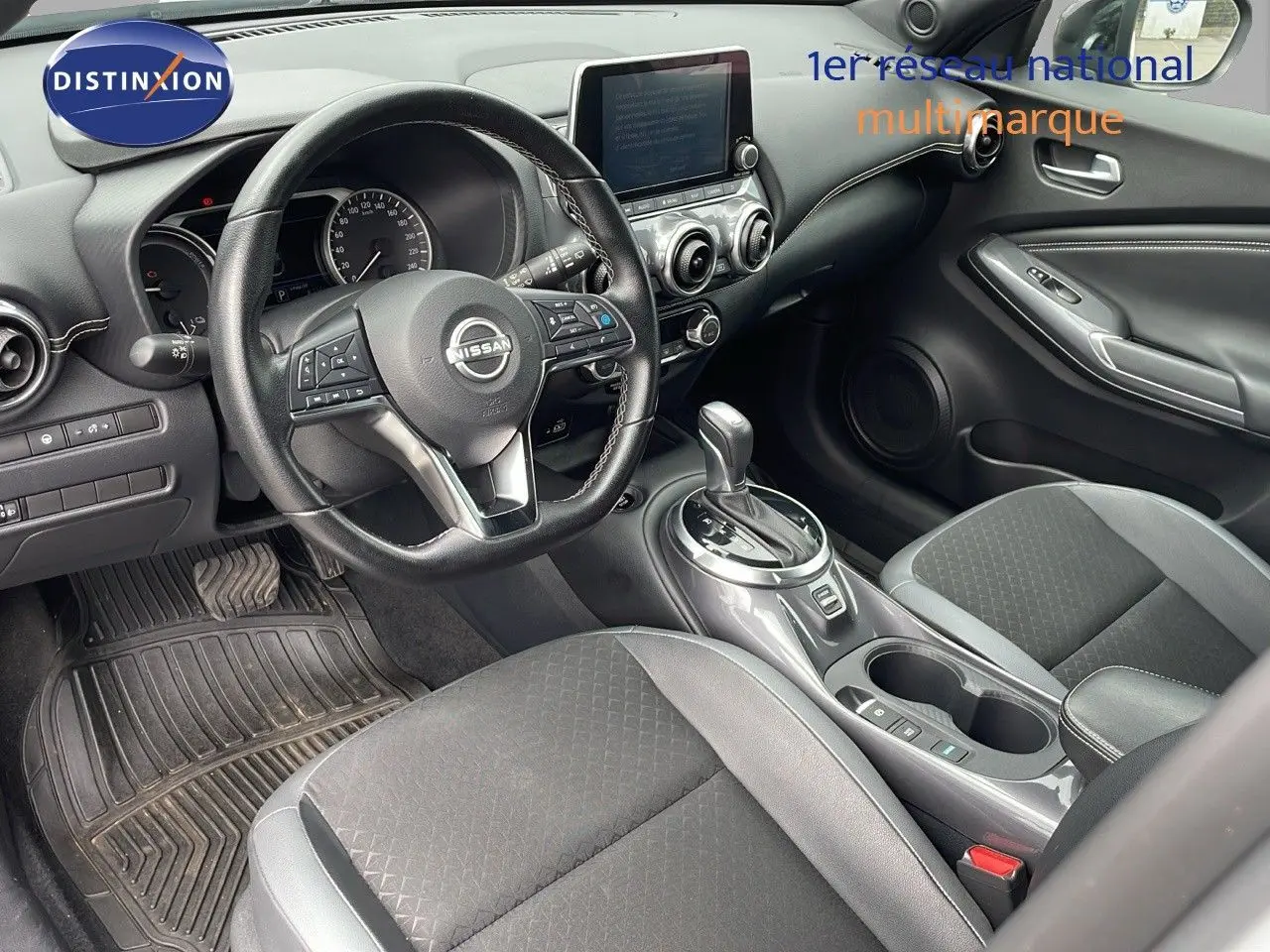 Intérieur du Nissan Juke Hybrid 2023 en gris perle, vue côté conducteur sur le tableau de bord et la console centrale.