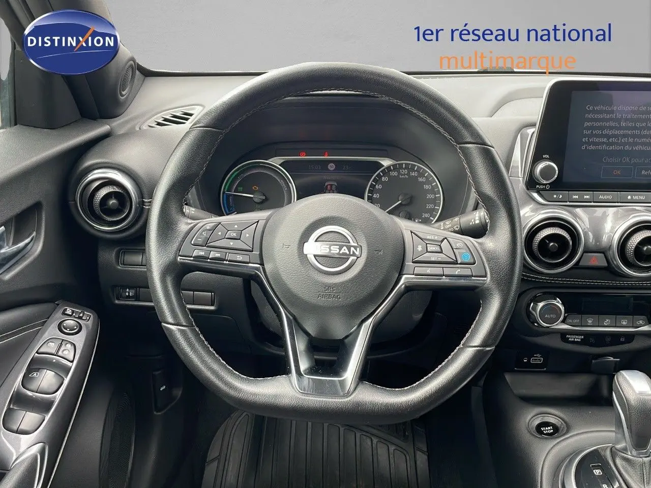 Vue centrée sur le volant cuir noir du Nissan Juke Hybrid 2023 avec tableau de bord et écran tactile visibles.
