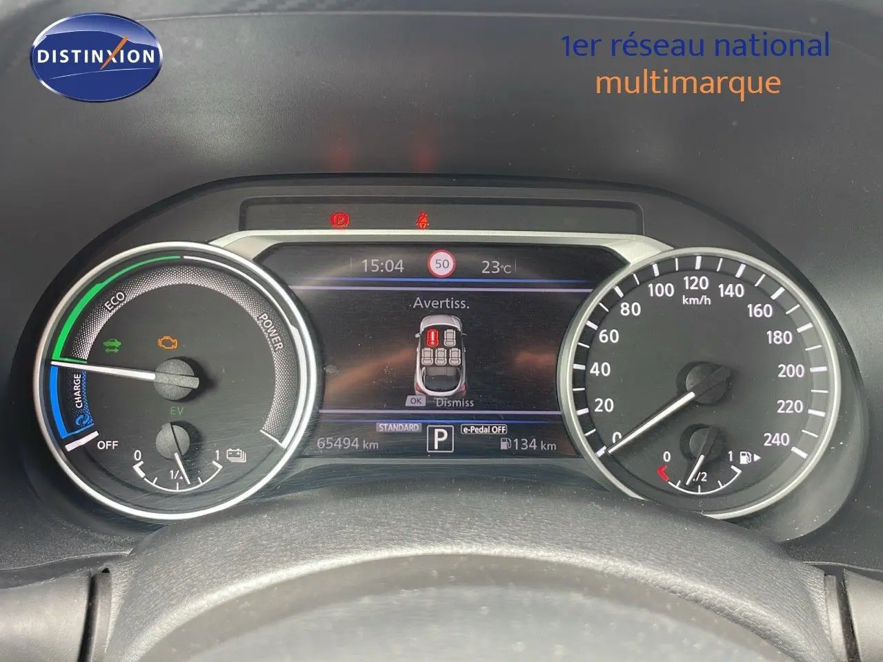 Tableau de bord du Nissan Juke Hybrid 2023 montrant les compteurs et l'écran d'alerte en affichage numérique.