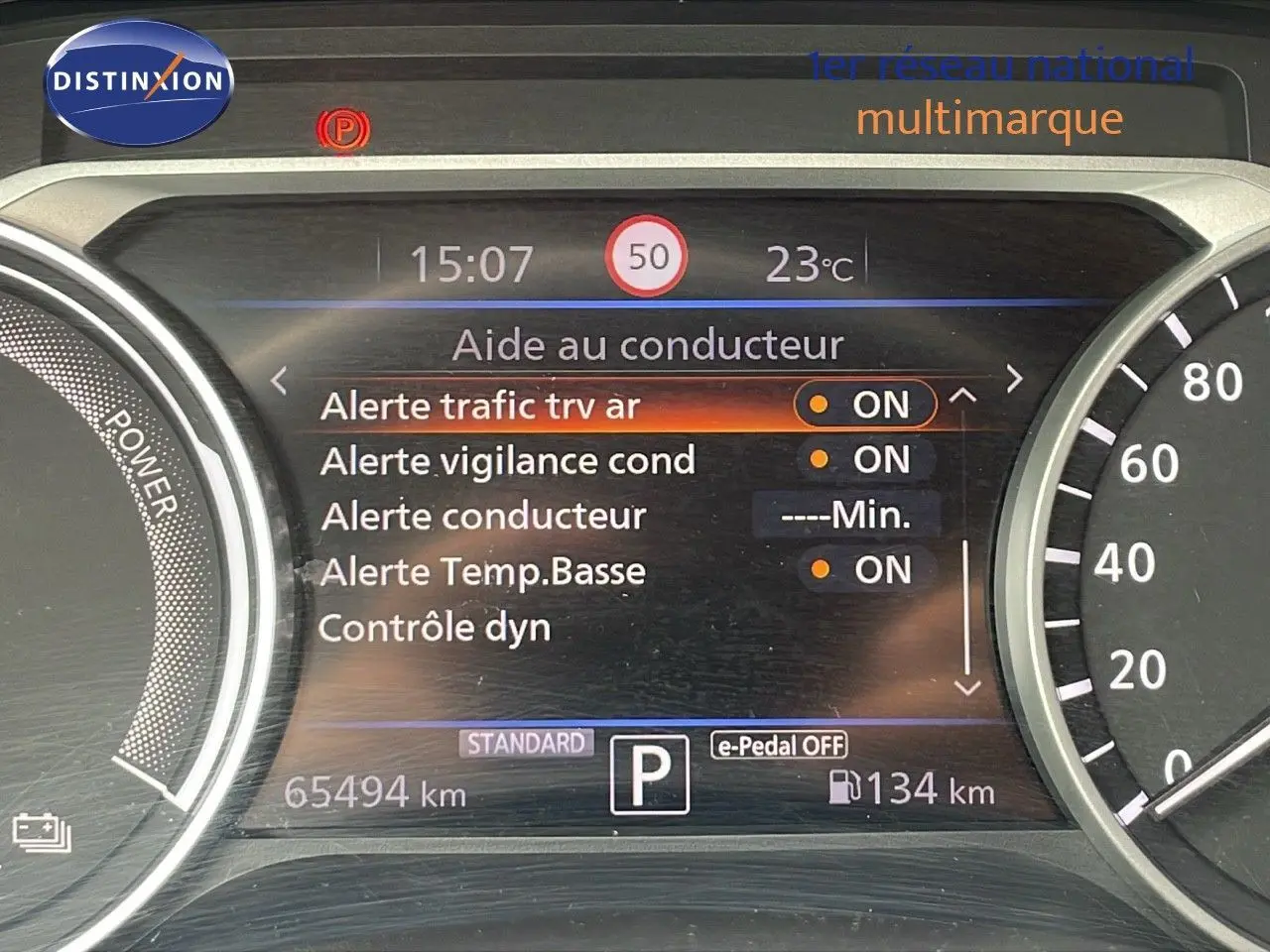 Tableau de bord du Nissan Juke Hybrid 2023 affichant les alertes conducteur et la vitesse, vue intérieure frontale.