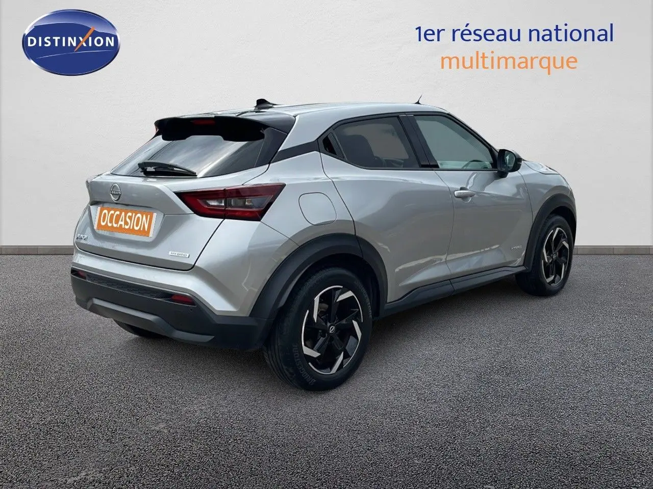 Vue 3/4 arrière droite d'un Nissan Juke hybride gris perle métal avec jantes noires et toit noir contrasté.