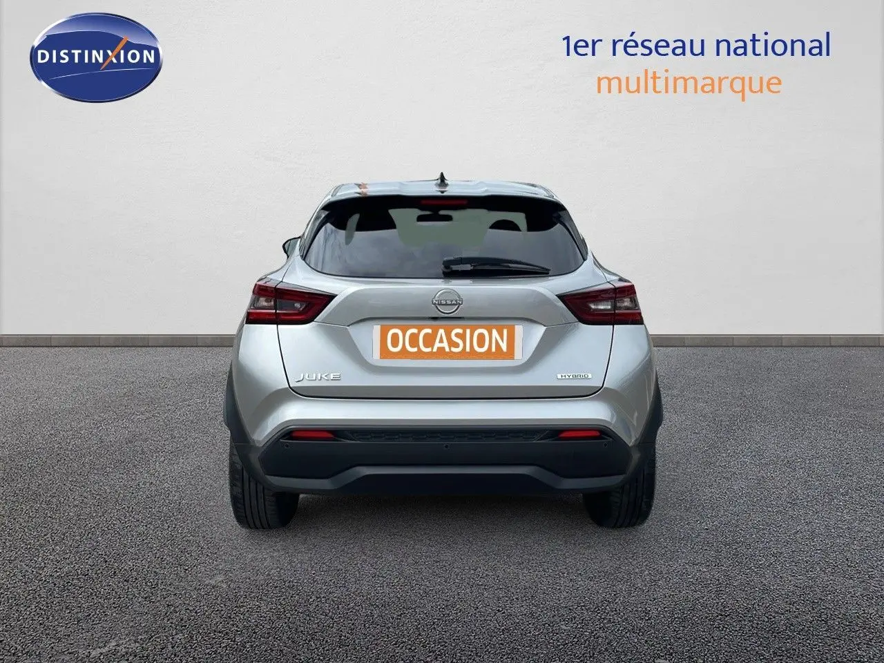 Vue arrière d'un Nissan Juke Hybrid 143ch gris perle métal, avec logo et feux arrière visibles.